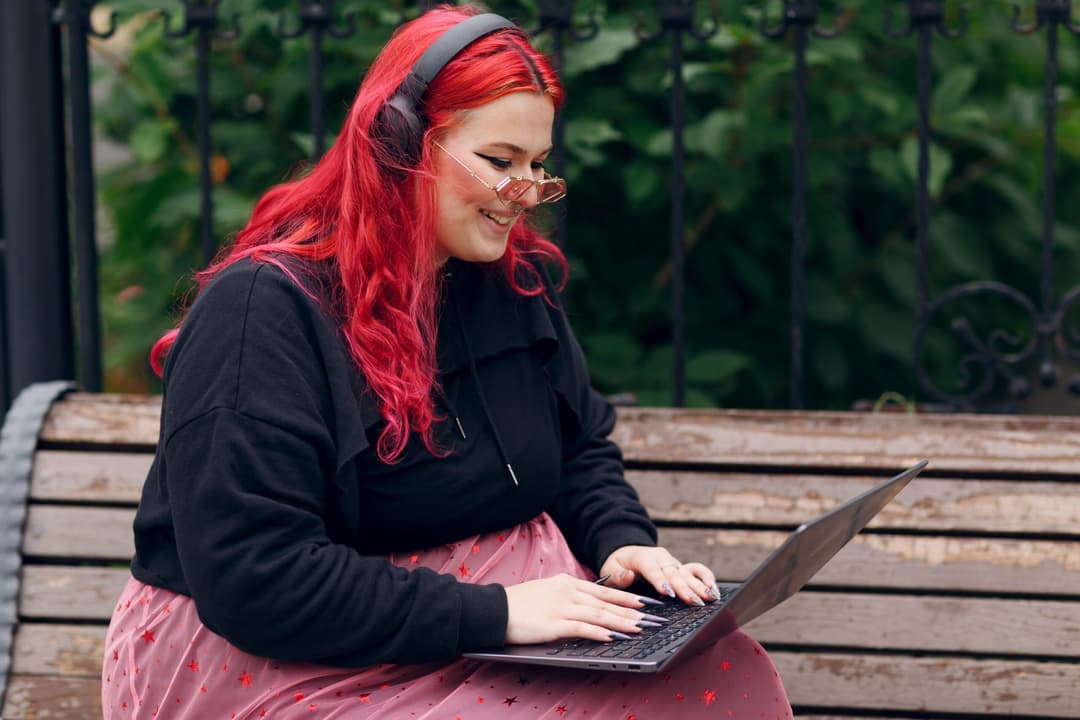 European,Plus,Size,Woman,Uses,Laptop,While,Sitting,On,Wooden